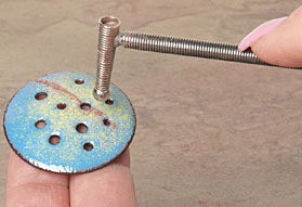 Using a tool to make the holes in the metal bigger